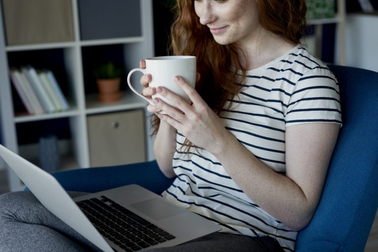 Woman drinking coffee and using her computer